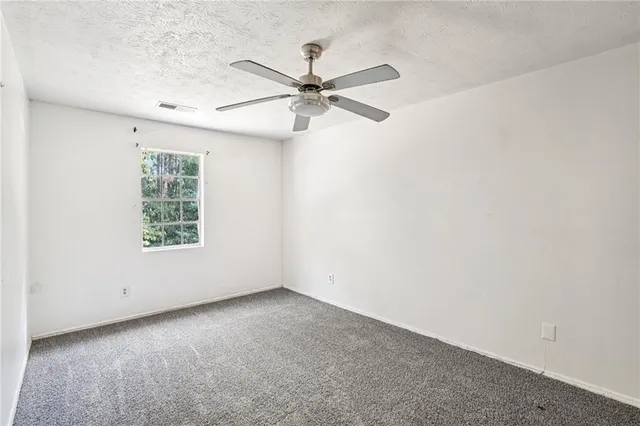 an empty room with a window and a fan