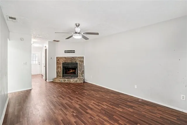 a view of an empty room with wooden floor fireplace and a window