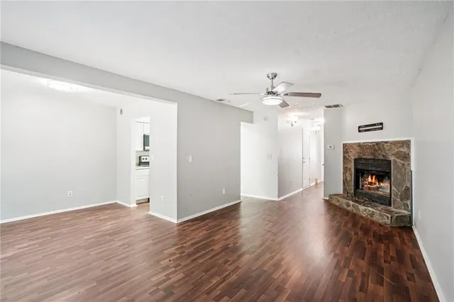 an empty room with wooden floor fireplace and windows