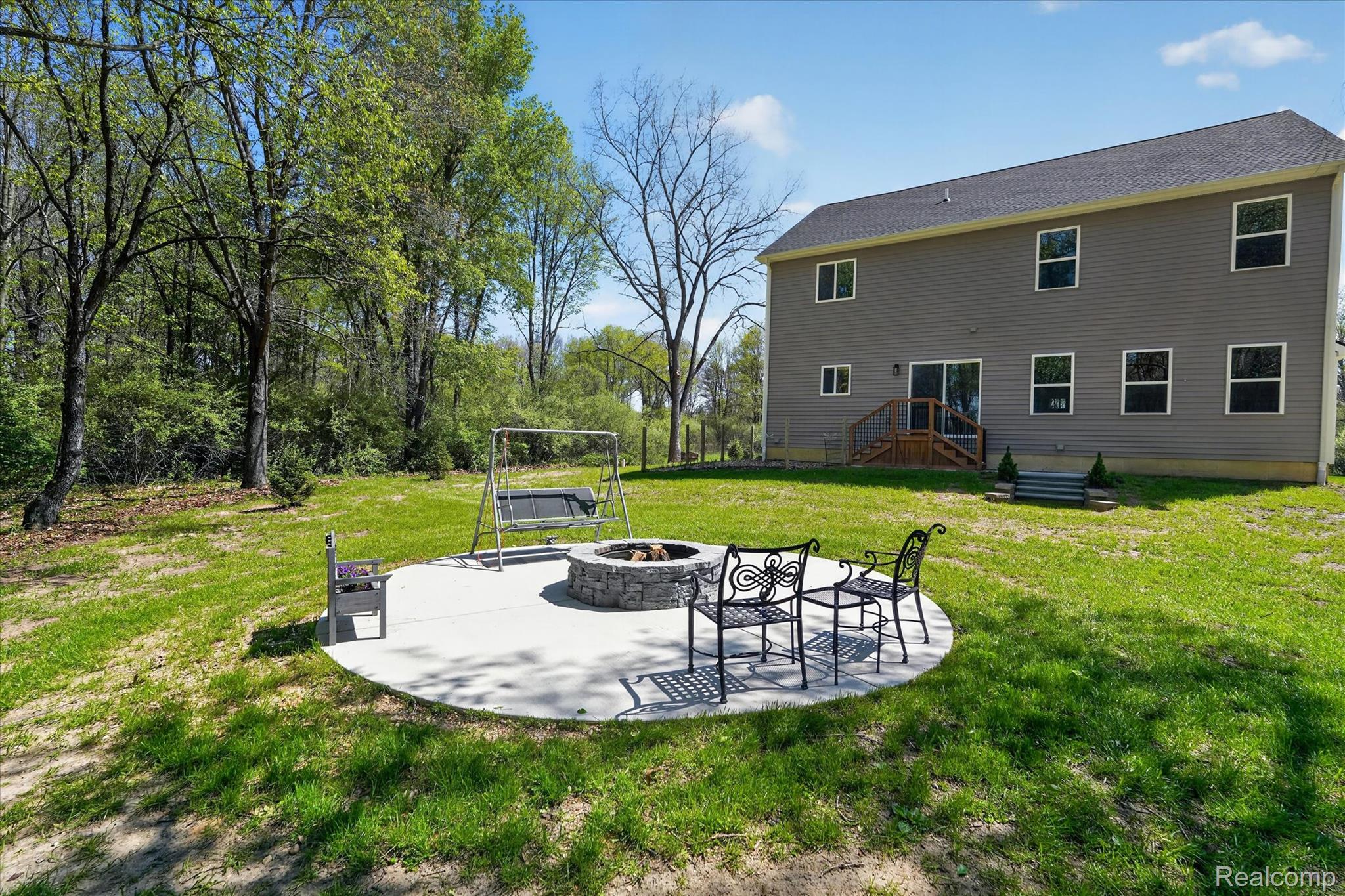 8130 Hinchey Road Pinckney, MI 48169 - Photo 45 of 62 Back of property featuring a fire pit, a patio, and a lawn