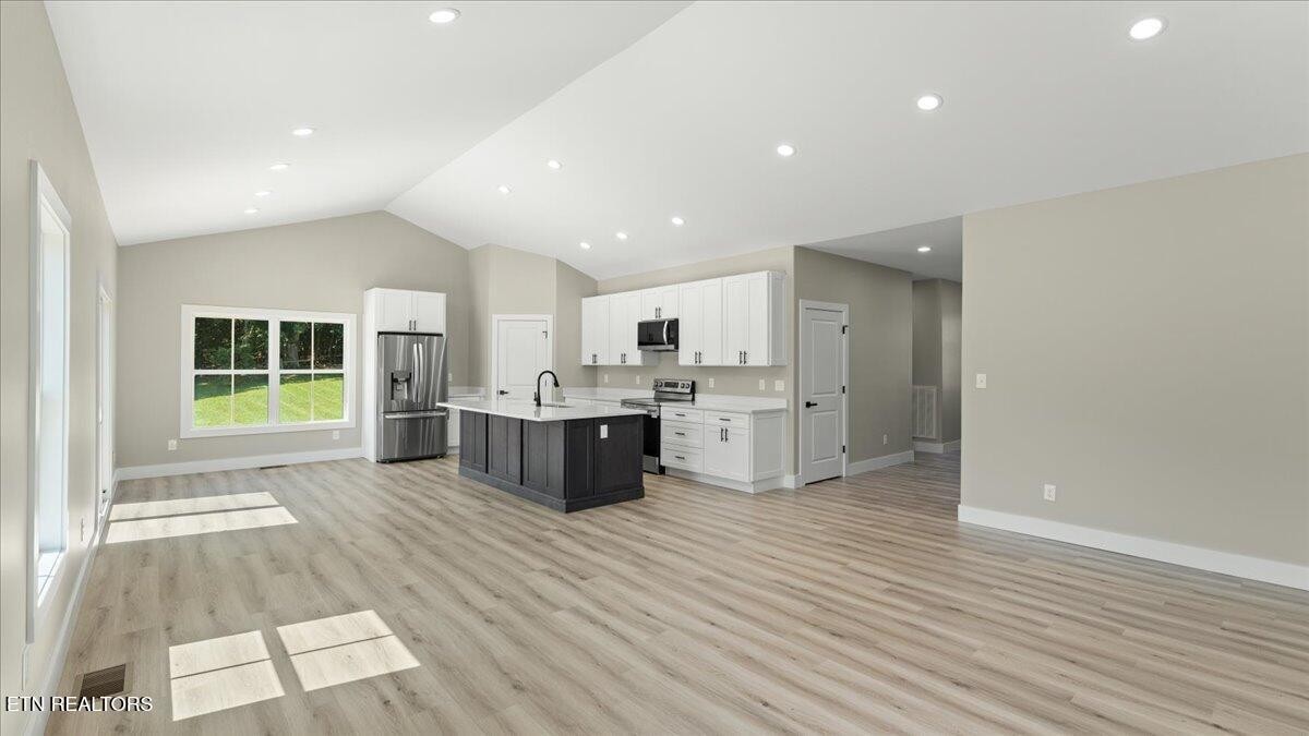 5817 Caldwell Road Loudon, TN 37774 - Photo 5 of 43 a large white kitchen with kitchen island a sink wooden floor and a refrigerator
