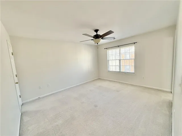 an empty room with windows and ceiling fan