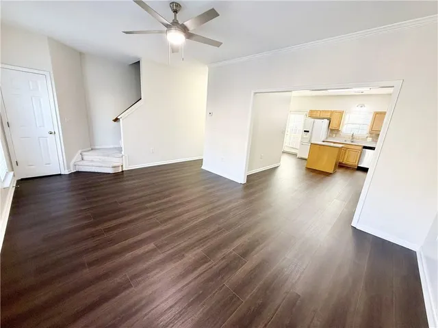 a view of an empty room with wooden floor and a ceiling fan