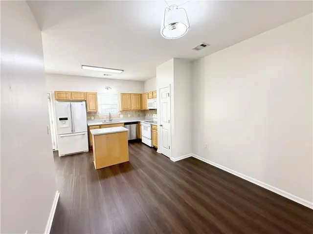 a room with kitchen island stainless steel appliances cabinets and wooden floor
