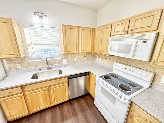 a kitchen with granite countertop a sink a stove and cabinets