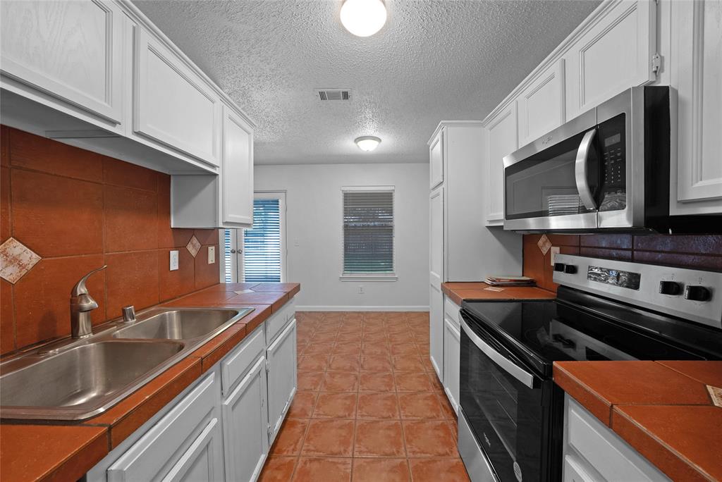 2910 Chisholm Trail Corinth, TX 76210 - Photo 14 of 30 a kitchen with stainless steel appliances a sink stove and microwave