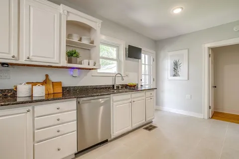 a kitchen with granite countertop white cabinets and window