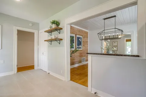 a view of an empty room with chandelier fan and wooden floor
