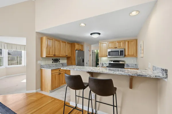 a kitchen with stainless steel appliances granite countertop a stove top oven a sink a refrigerator with white cabinets and wooden floor