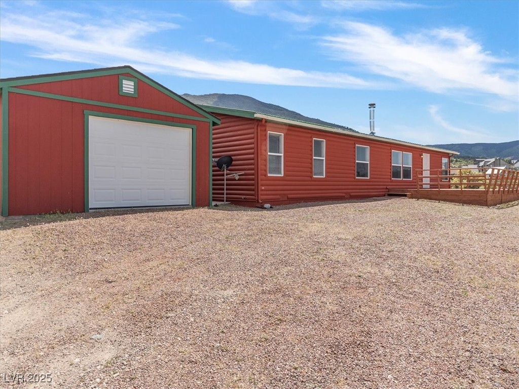 70 West Bonanza Road Las Vegas, NV 89124 - Photo 40 of 71 View of front of property with dirt driveway, log veneer siding, an outdoor structure, a mountain view, and a garage