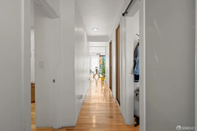 a view of a hallway with wooden floor and a living room