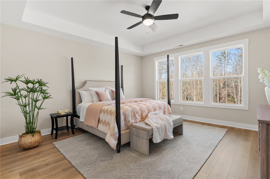 3401 Split Oak Circle Seneca, SC 29678 - Photo 7 of 8 This primary bedroom features elegant wood flooring and serene outdoor views, creating a peaceful retreat.