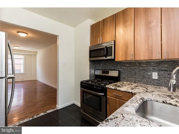 a kitchen with granite countertop a stove a sink and a microwave