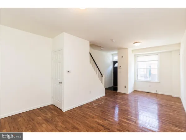a view of an empty room with wooden floor and stairs