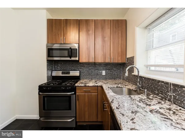 a kitchen with granite countertop a stove sink and cabinets