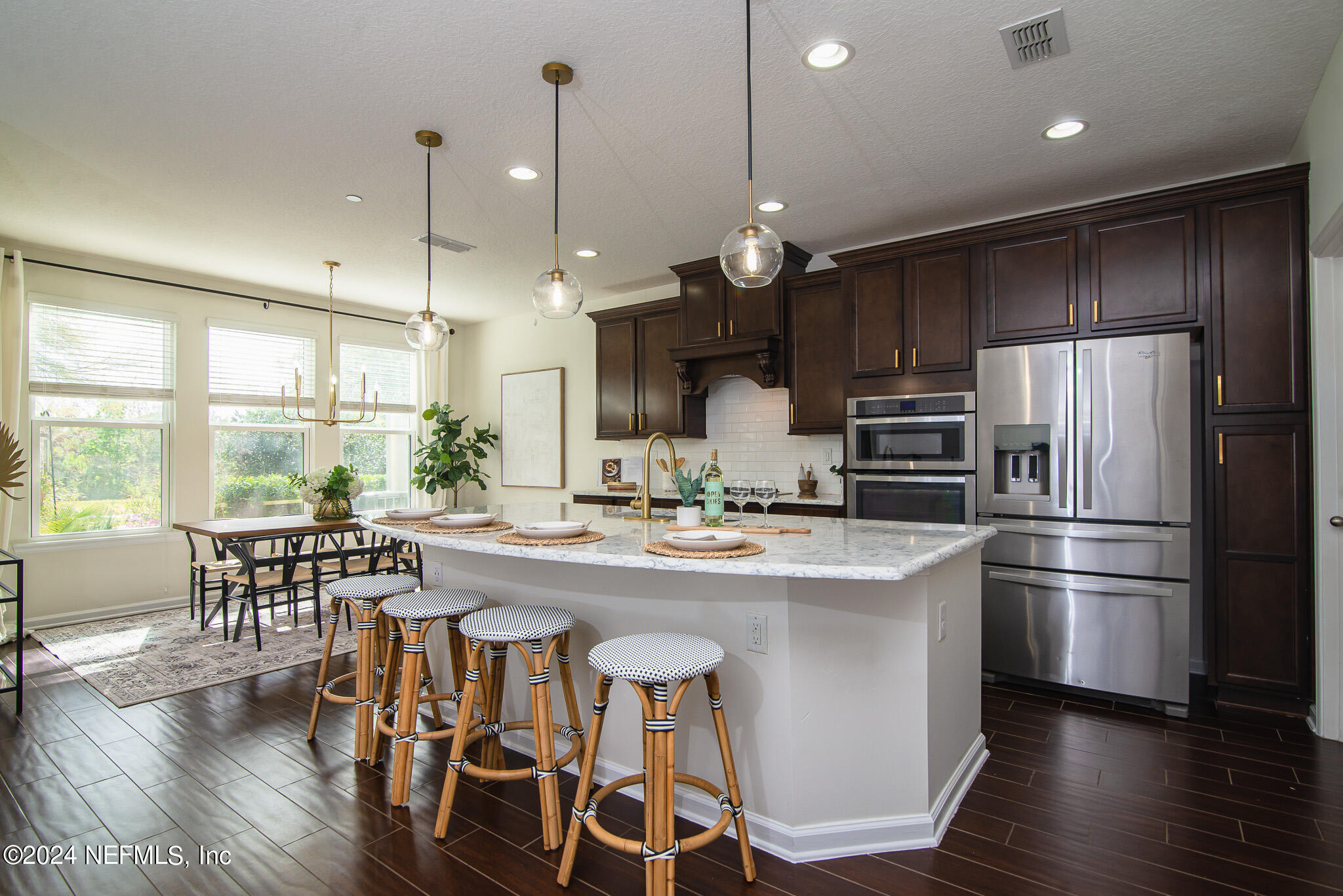 a kitchen with stainless steel appliances a dining table chairs stove refrigerator and wooden floor