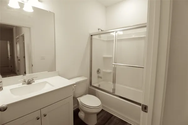 an empty room with wooden floor cabinet and windows