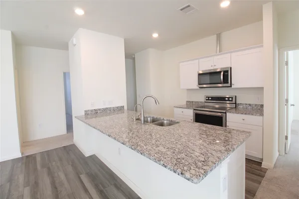 a kitchen with kitchen island granite countertop a sink stove and refrigerator