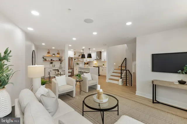 a living room with furniture kitchen view and a flat screen tv