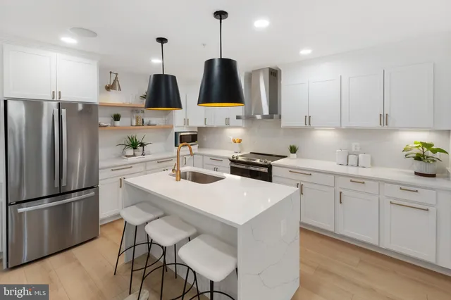 a kitchen with stainless steel appliances granite countertop a sink a stove a refrigerator and island with wooden floor