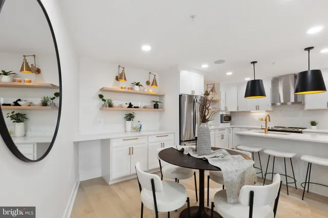 a kitchen with stainless steel appliances granite countertop a sink a stove a microwave a dining table and chairs with wooden floor