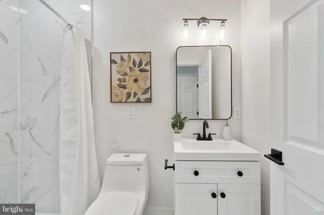 a bathroom with a sink vanity mirror and toilet