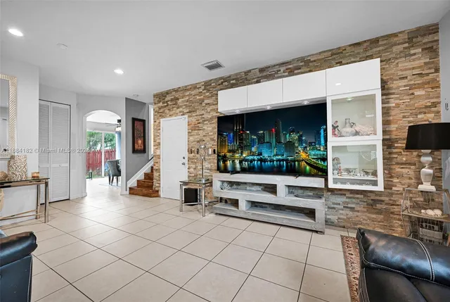a view of living room kitchen with stainless steel appliances kitchen island granite countertop living room and rug