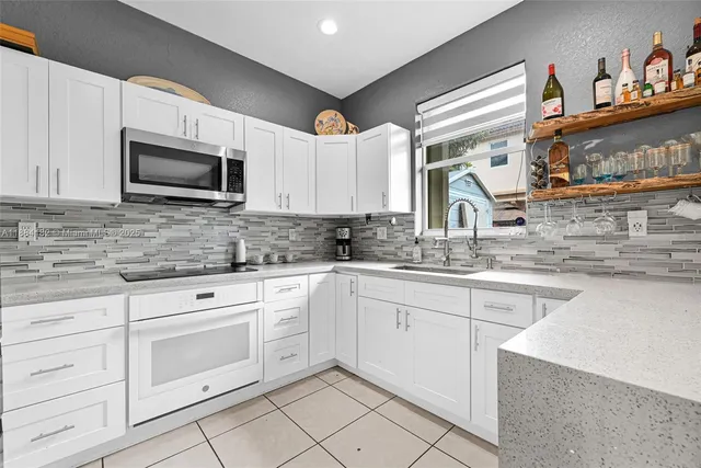 a kitchen with granite countertop white cabinets sink and stainless steel appliances