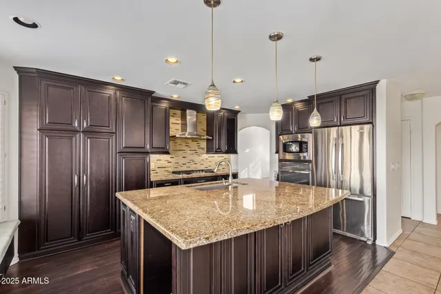 a kitchen with kitchen island granite countertop a refrigerator a sink and wooden cabinets