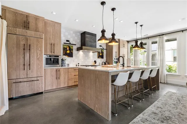 a kitchen with kitchen island granite countertop a table chairs refrigerator and sink