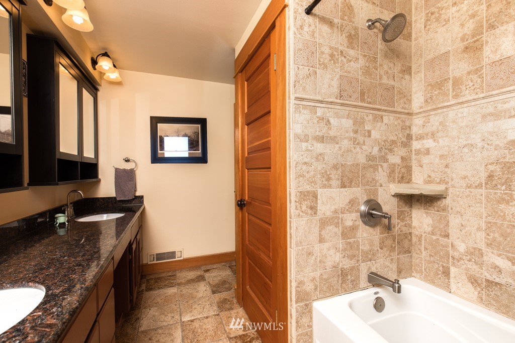 6815 Skipley Road Snohomish, WA 98290 - Photo 19 of 36 a bathroom with a granite countertop sink a mirror a bathtub and shower
