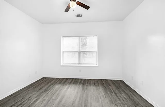 an empty room with a window and wooden floor