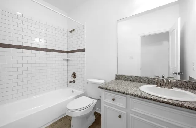 a bathroom with a granite countertop toilet a sink and a bathtub