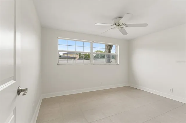 a view of an empty room with window and a kitchen