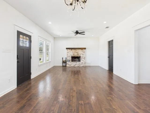 an empty room with wooden floor fireplace and windows