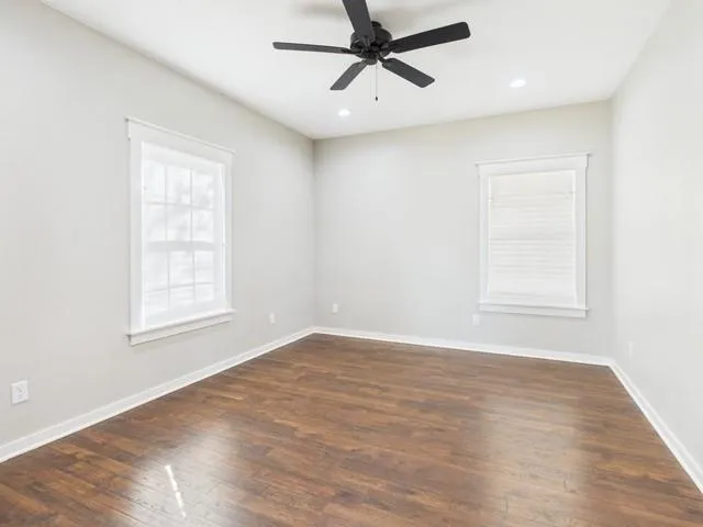 a view of an empty room with wooden floor and a window