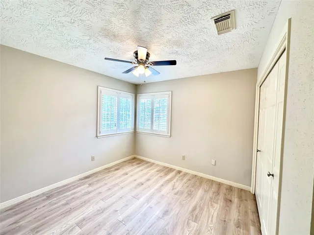 an empty room with windows and fan