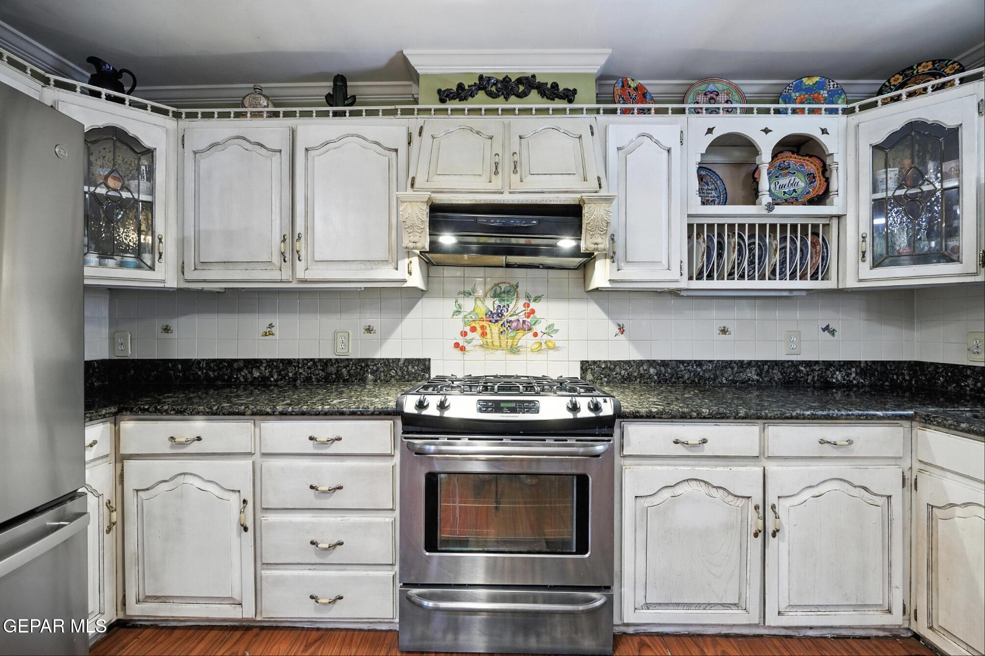 190 Polo Inn Road El Paso, TX 79915 - Photo 20 of 58 a kitchen with granite countertop a stove a sink and a microwave