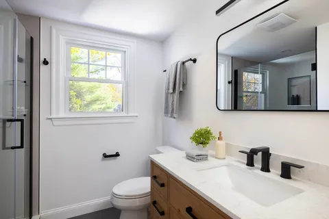 a bathroom with a granite countertop sink toilet and a mirror