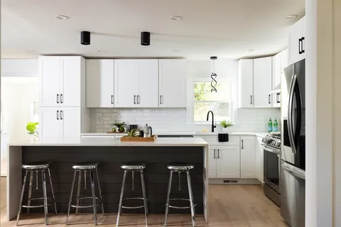 a kitchen with stainless steel appliances a sink a stove a refrigerator cabinets and a window