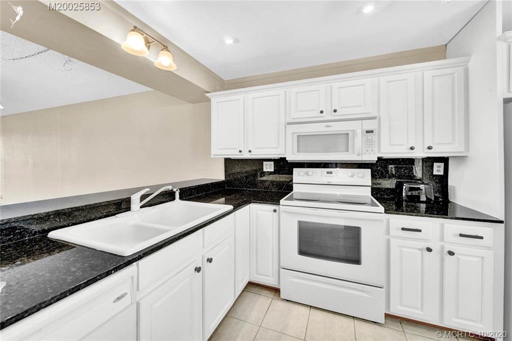 1950 Southwest Palm City Road, Unit 13305 Stuart, FL 34994 - Photo 7 of 28 a kitchen with granite countertop white cabinets and white appliances