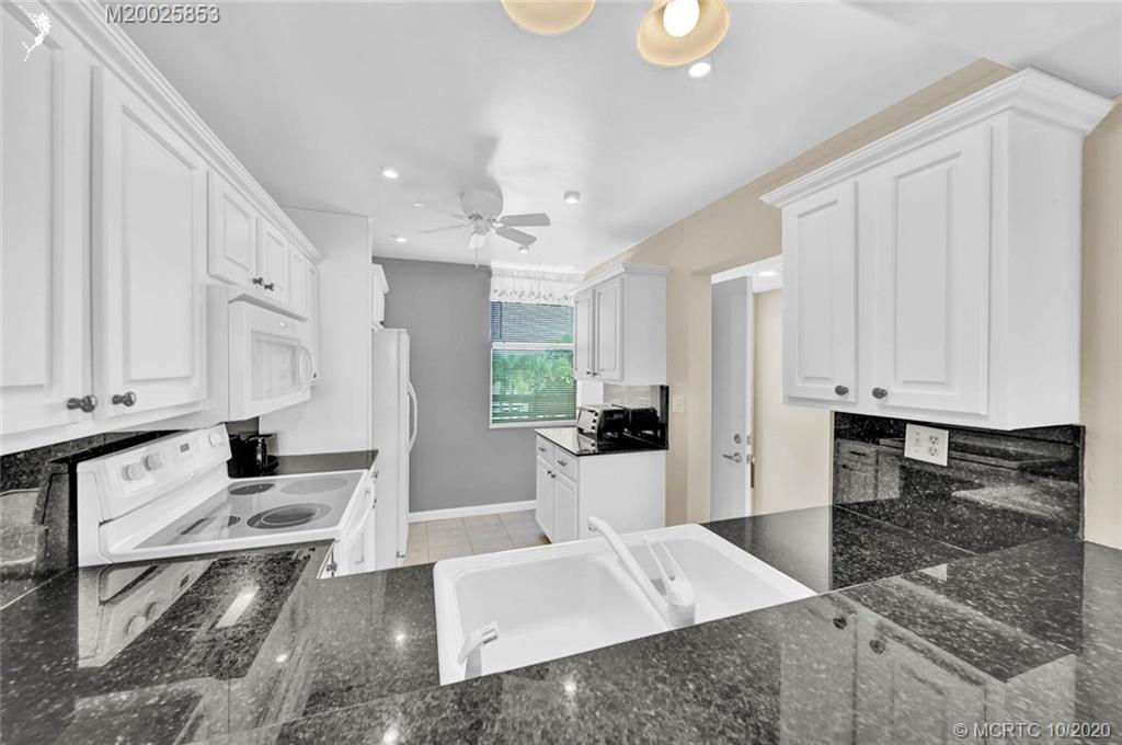 1950 Southwest Palm City Road, Unit 13305 Stuart, FL 34994 - Photo 9 of 28 a large white kitchen with white cabinets and a granite counter tops