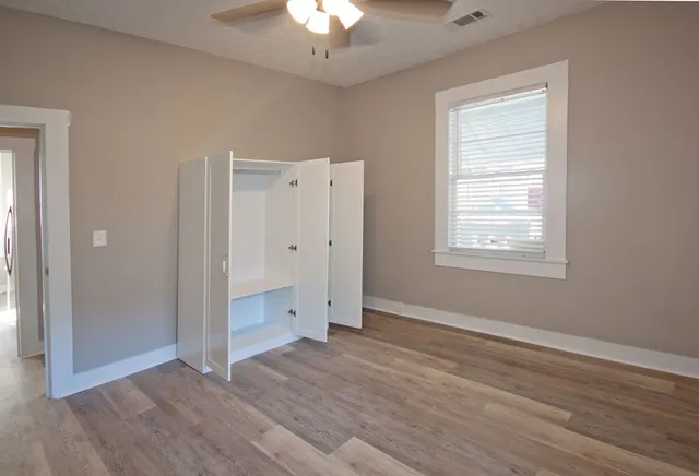 an empty room with wooden floor cabinet and windows