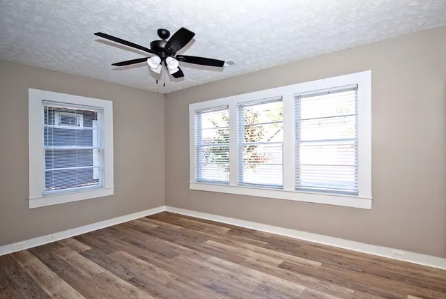 a view of empty room with wooden floor and fan