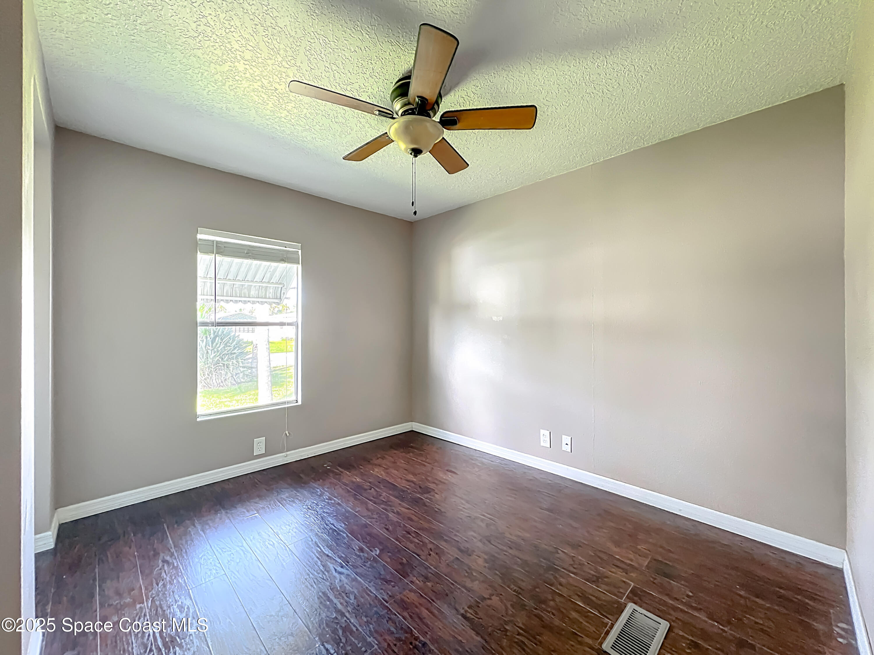 425 Baker Road Merritt Island, FL 32953 - Photo 13 of 27 an empty room with wooden floor fan and windows