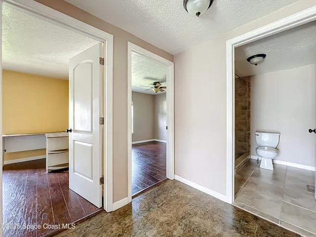 a view of a hallway with bathroom and wooden floor