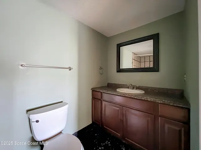 a bathroom with a granite countertop sink toilet and mirror
