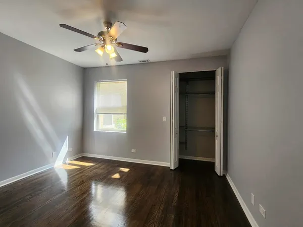 an empty room with wooden floor chandelier fan and windows