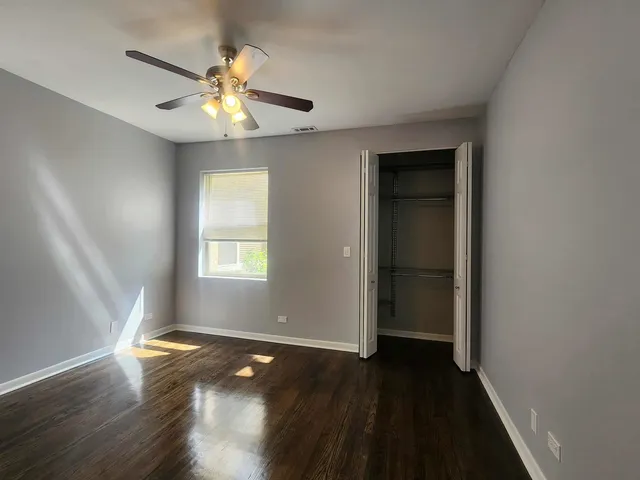 an empty room with wooden floor chandelier fan and windows