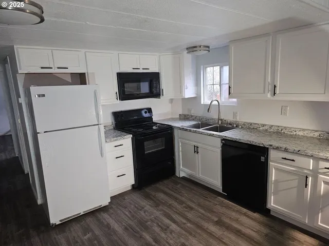 a kitchen with white cabinets and black appliances